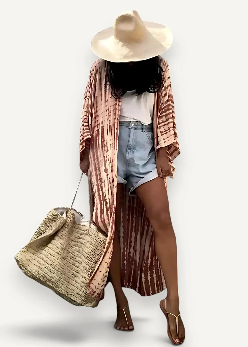 Woman wearing the rust striped beach kimono maxi open over a white tee and denim shorts, with a straw hat and woven beach bag
