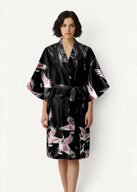 Black silk robe in satin fabric with vibrant pink and white cranes in flight pattern on front side