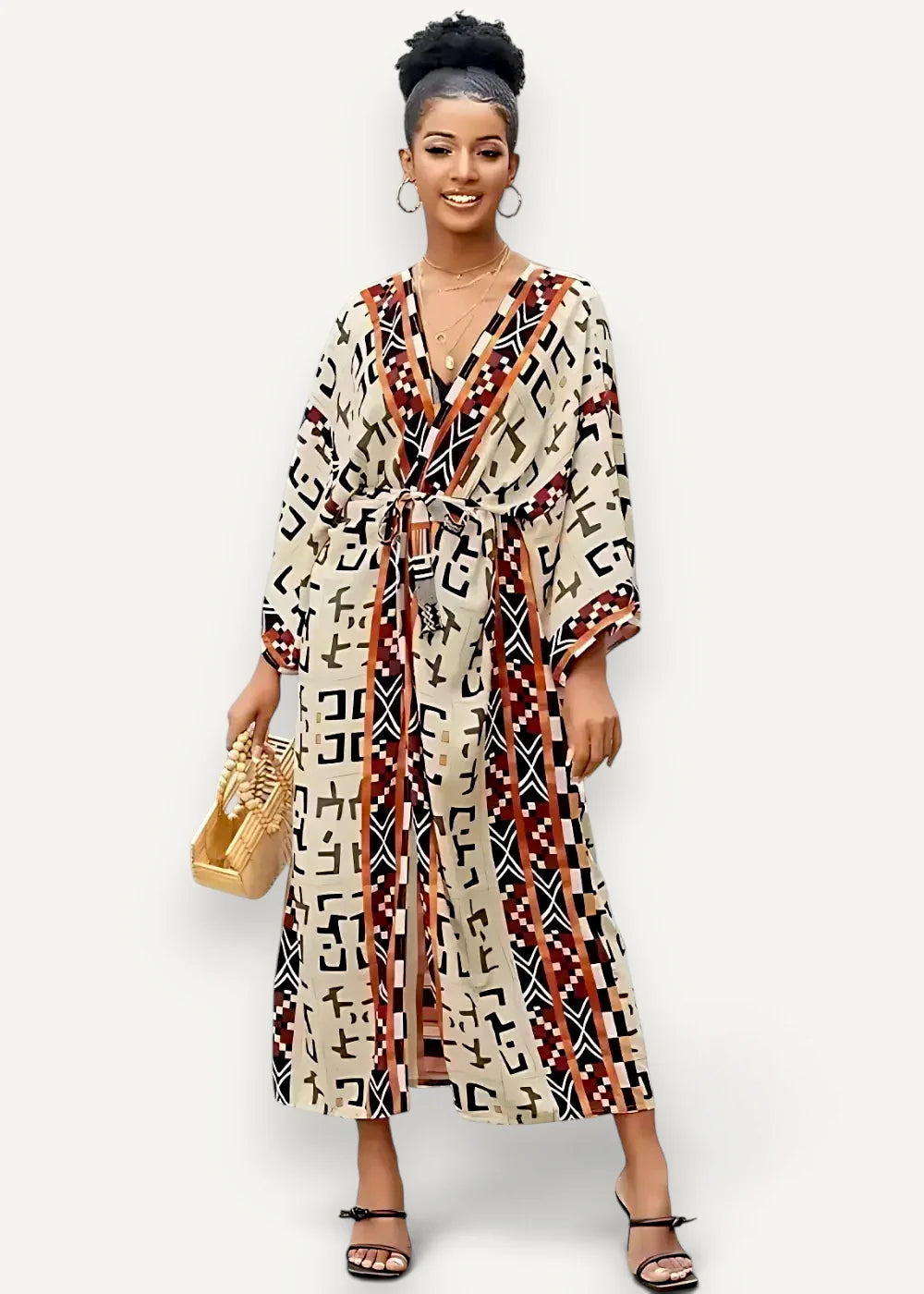 A woman wearing a cream black and terracotta long flowing wrap dress with an intricate geometric pattern