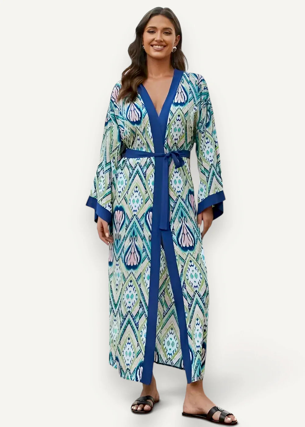 A woman wearing a boho kimono duster with teal floral geometric pattern and royal blue trim in flowing fabric
