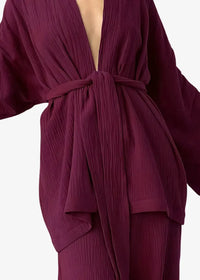 A flowing deep burgundy kimono pajama robe with ribbed texture wide sleeves tied at the waist