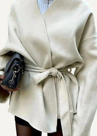 Woman wearing a cream casual kimono jacket with a soft draped shape and a belted waist