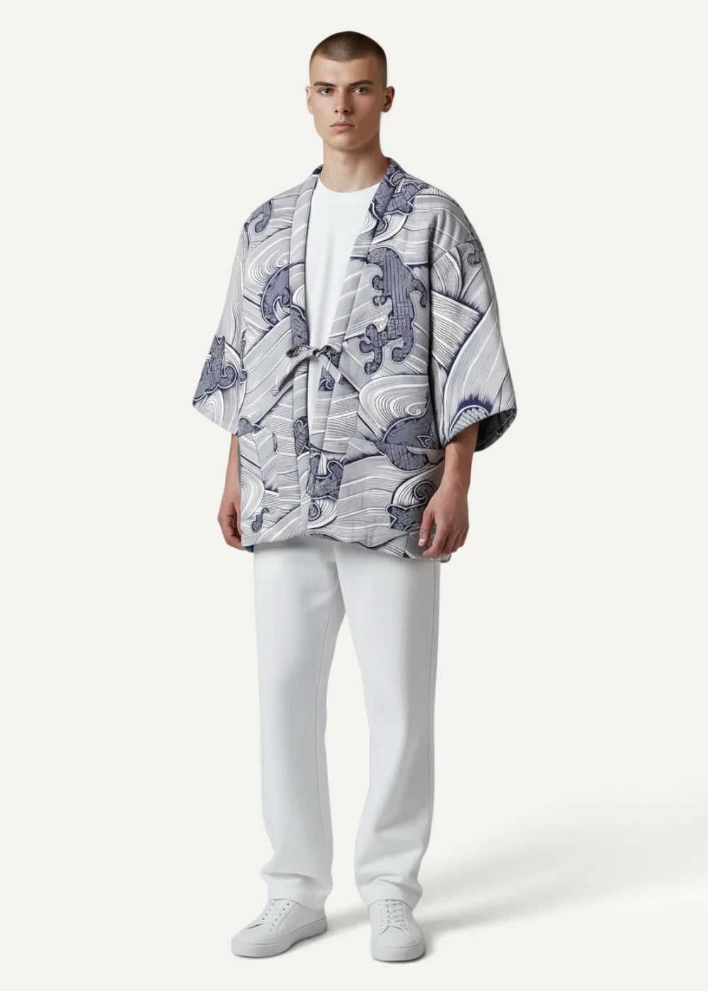 A man wearing a cotton kimono jacket in light gray and navy blue with wave and creature motifs