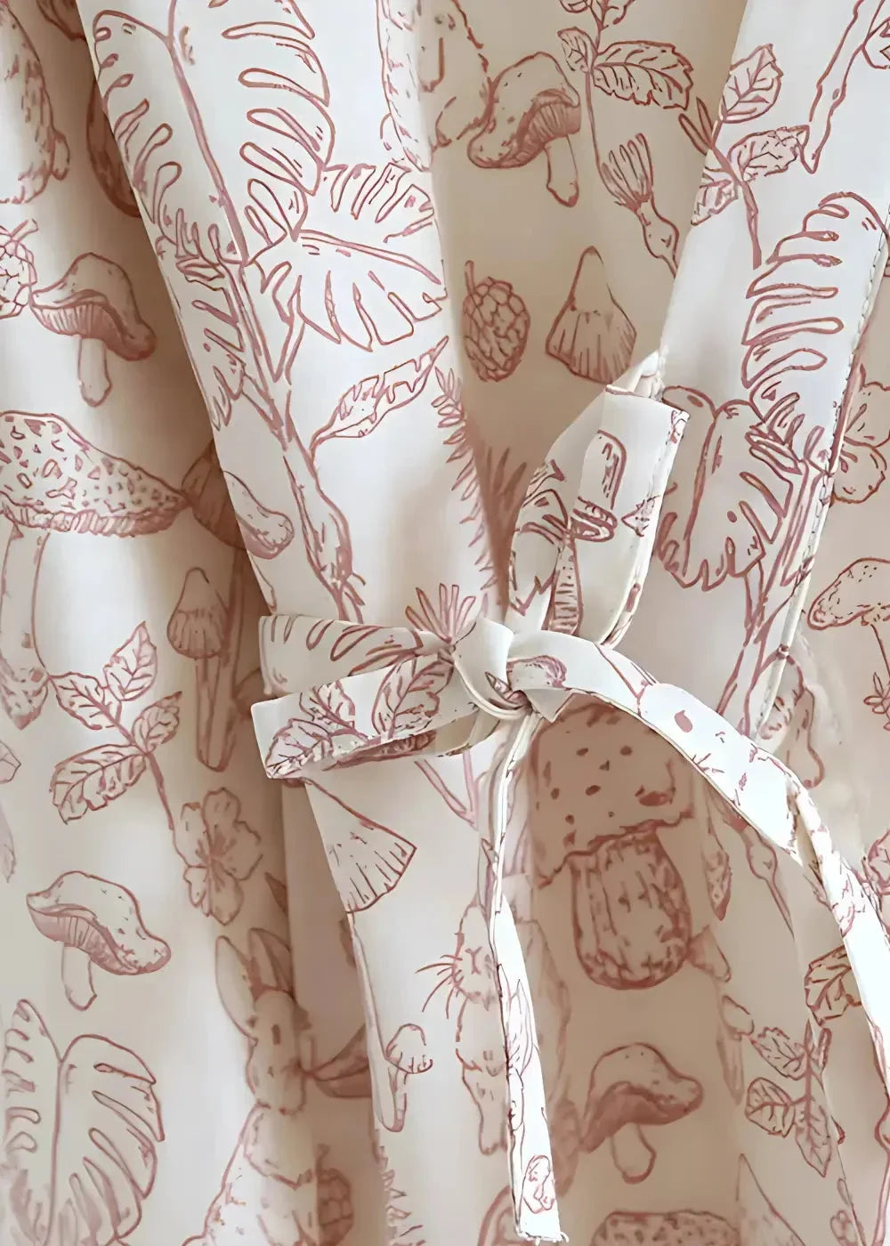 Cream-colored cotton kimono robe short with a delicate reddish-brown botanical and whimsical animal print tied at the waist