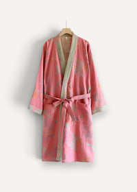 A soft pink cotton kimono robe with floral pattern sage green trim and matching belt hanging on wooden hanger
