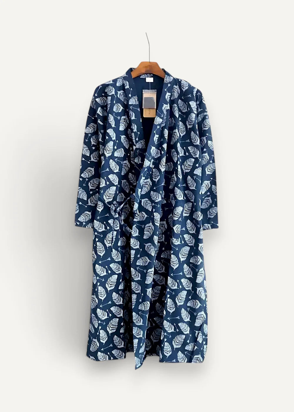 A navy blue cotton men’s kimono robe with a white leaf pattern hanging on a wooden hanger