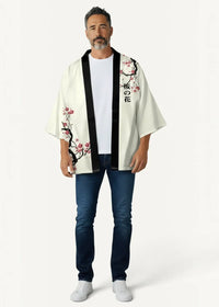 Cropped cream-colored kimono jacket with black trim and pink cherry blossom designs featuring japanese characters