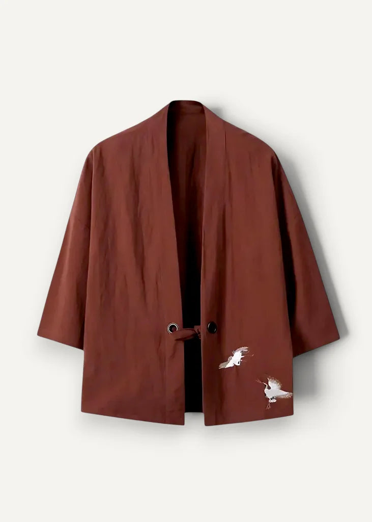 A rich rust-colored embroidered haori jacket with delicate white crane embroidery on the lower front and three-quarter sleeves