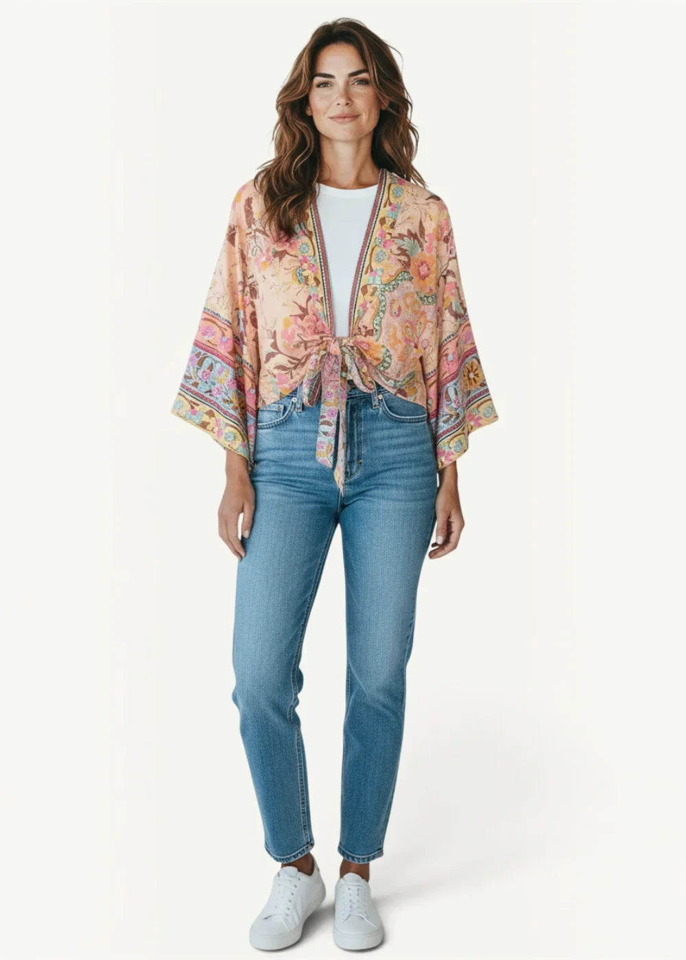 A soft peach-colored floral beach kimono with a tie-front design and wide flowing sleeves made from lightweight fabric