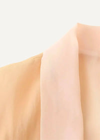 A soft peach-colored silk floral embroidered kimono jacket with delicate flowing fabric and subtle sheen
