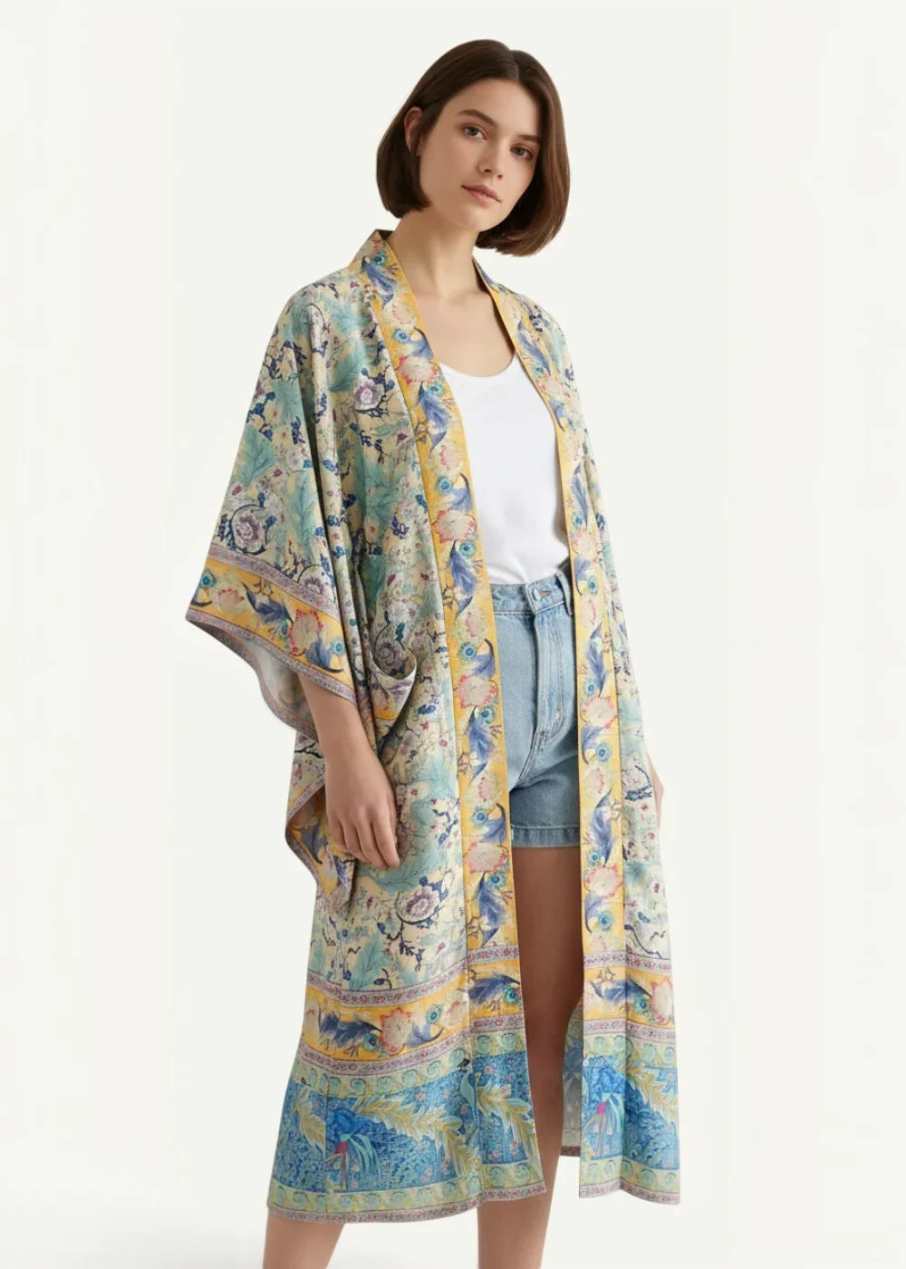 A flowing long-sleeved floral kimono beach cover up in soft teal and gold with intricate bird motifs