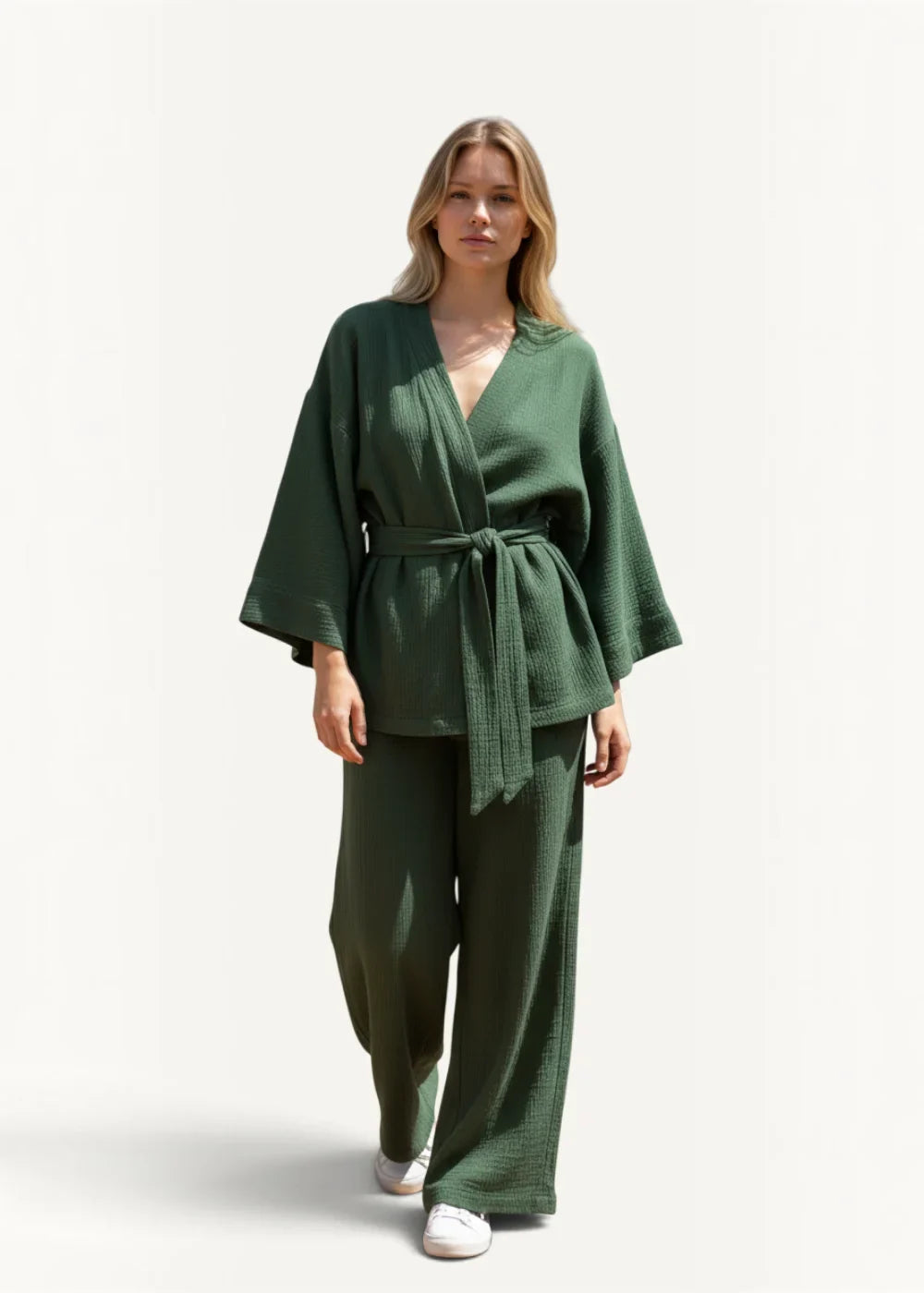 A woman wearing green cotton kimono pajamas with textured wrap top wide sleeves and high-waisted tied pants