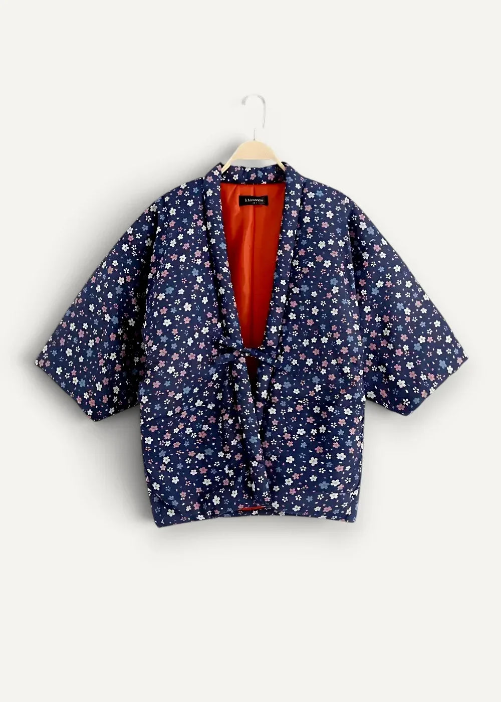 A navy blue quilted Japanese kimono jacket for women with white and light pink floral pattern and orange lining