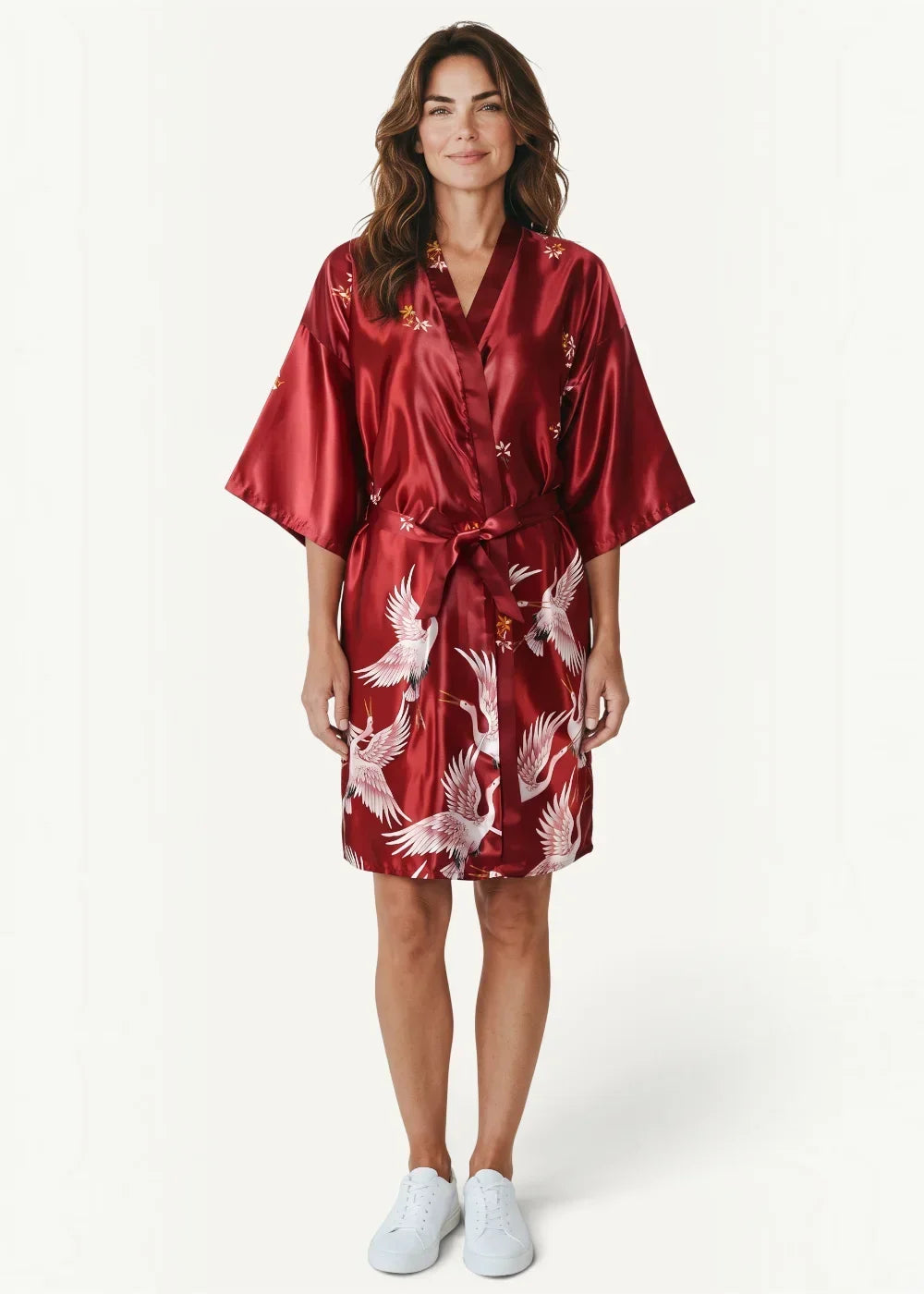 A rich red satin japanese kimono robe for females featuring white cranes and floral accents tied at the waist