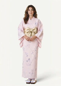 A delicate pink Japanese print kimono with lavender floral patterns and a wide gold obi sash tied in a bow