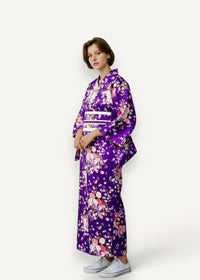 A vibrant purple Japanese kimono with delicate pink and white floral patterns and a contrasting white obi belt