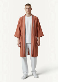 A terracotta textured cotton kimono bathrobe for men with white piping and subtle checkered zipper detail