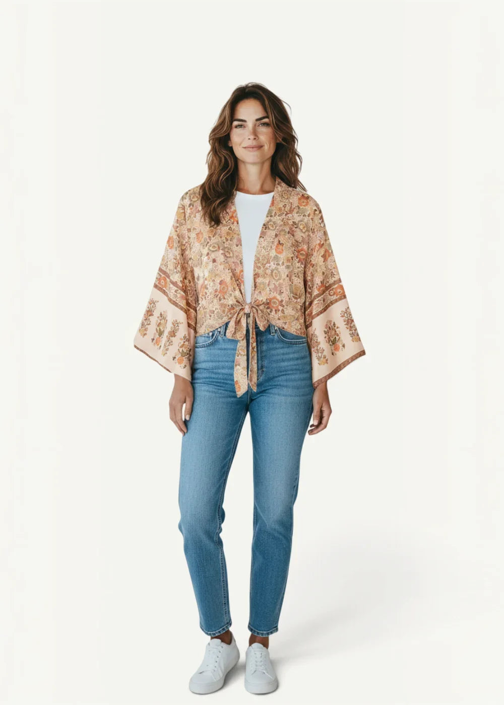 A soft peach-colored kimono beach cover up jacket with delicate floral pattern and wide flared sleeves tied at front
