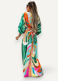 A vibrant long-sleeved kimono beach dress with bold tropical print in green orange pink and teal colors