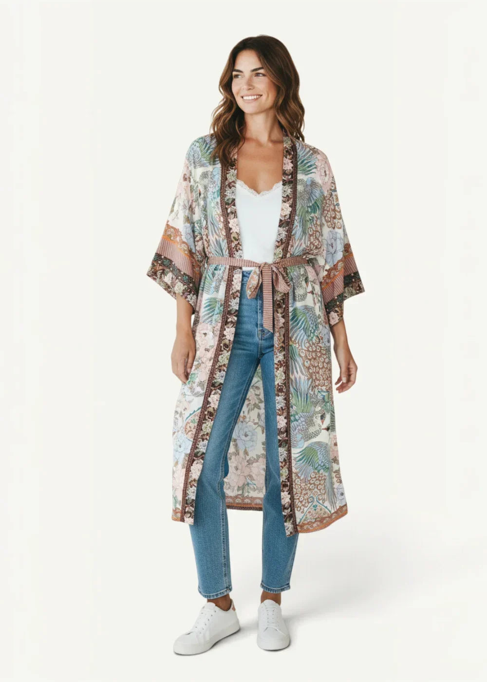 A woman wearing a pastel tropical floral kimono duster cardigan with wide sleeves and a matching belt