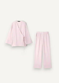 A soft blush pink kimono linen pajama set with a wrap-style top and wide-leg pants made of lightweight cotton