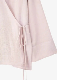 A soft blush pink kimono linen wrap dress with lightweight textured fabric and a delicate self-tie belt at the waist