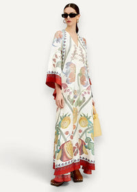 A white kimono maxi dress with vibrant botanical fruit and leaf print in red green yellow and brown with red trim