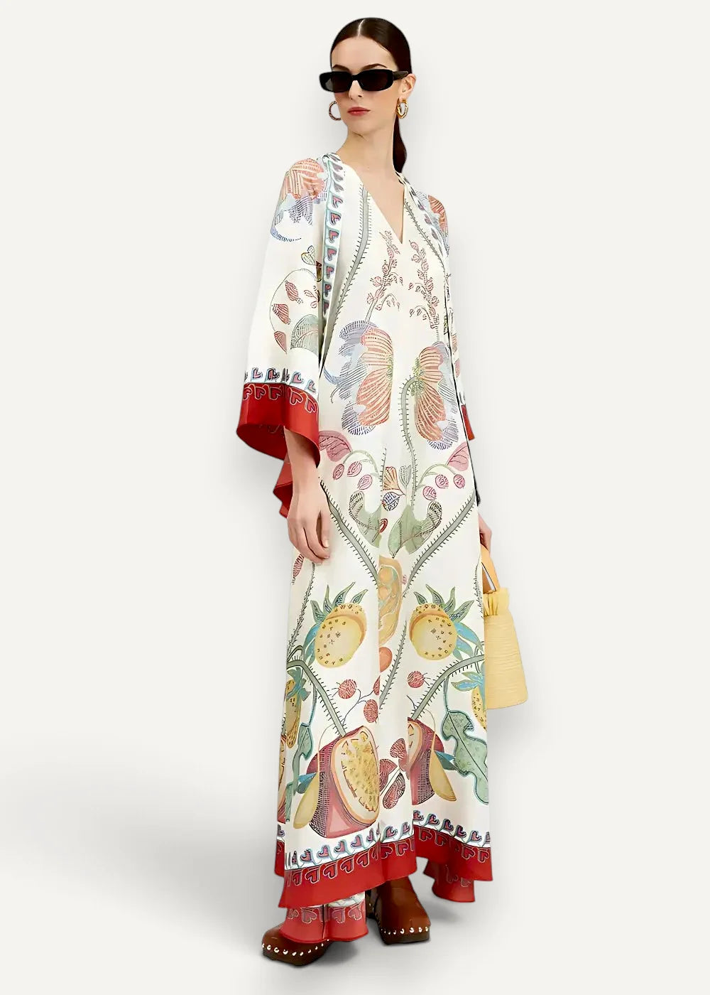 A white kimono maxi dress with vibrant botanical fruit and leaf print in red green yellow and brown with red trim