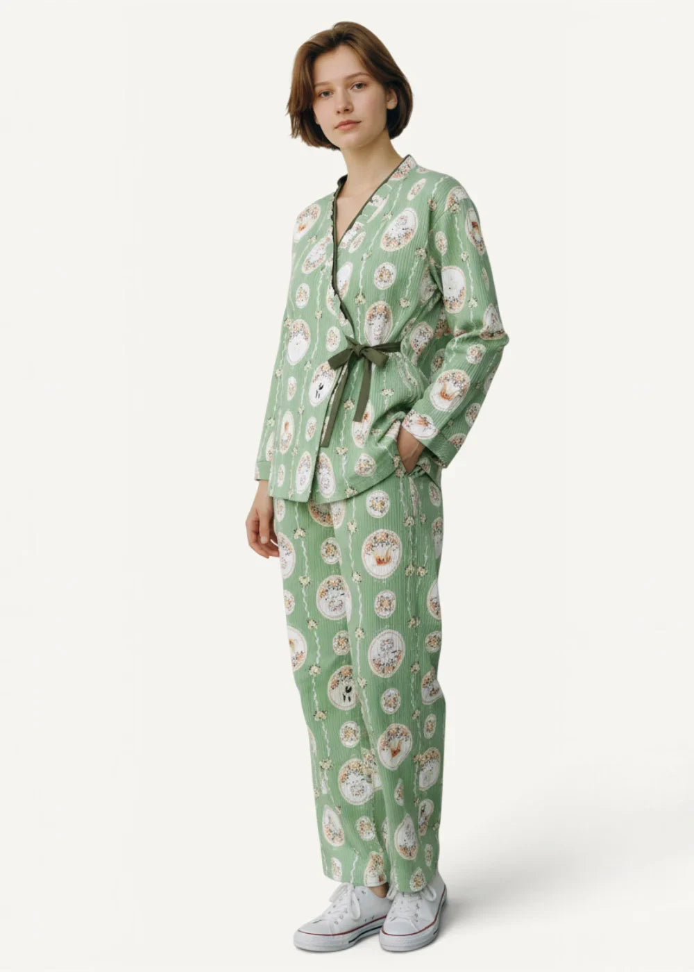 A woman wears a green kimono pajama set with a circular whimsical pattern and a dark olive waist belt