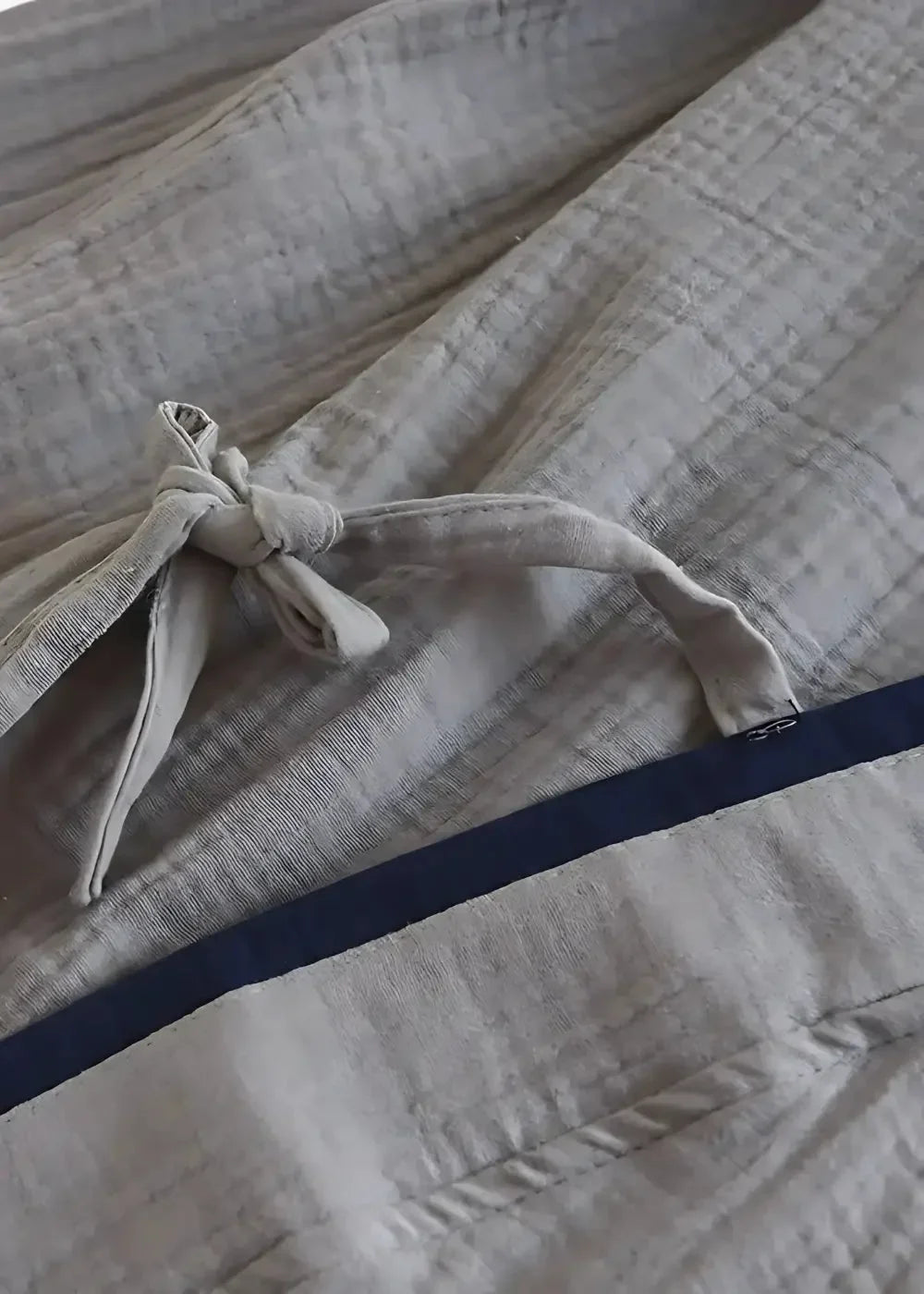 Light gray quilted kimono style pajama set with navy blue trim and matching drawstring tied in a knot