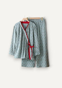 Light blue kimono style pajamas with subtle floral pattern v neck top tied with red ribbon and matching shorts