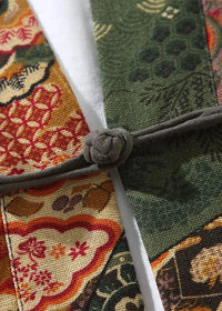 Linen kimono jacket with intricate red and green patterns on textured fabric fastened by a dark gray braided cord knot