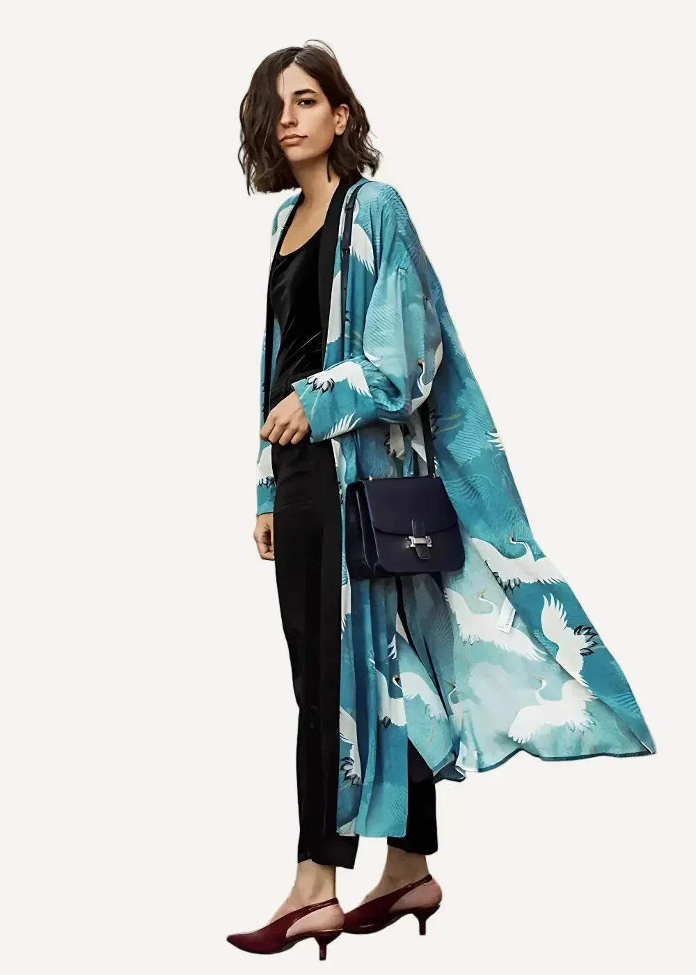Long kimono duster in flowing turquoise and white silk with crane pattern worn over black attire