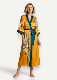 Long satin kimono robe in golden-yellow satin with teal blue floral trim and matching belt tied at the waist