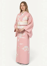 A soft pink long silk robe with delicate floral and cloud patterns and a white obi belt with gold detailing