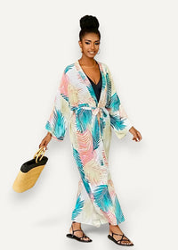 Long white kimono dress with long sleeves and vibrant tropical teal pink and cream palm leaf print on light fabric