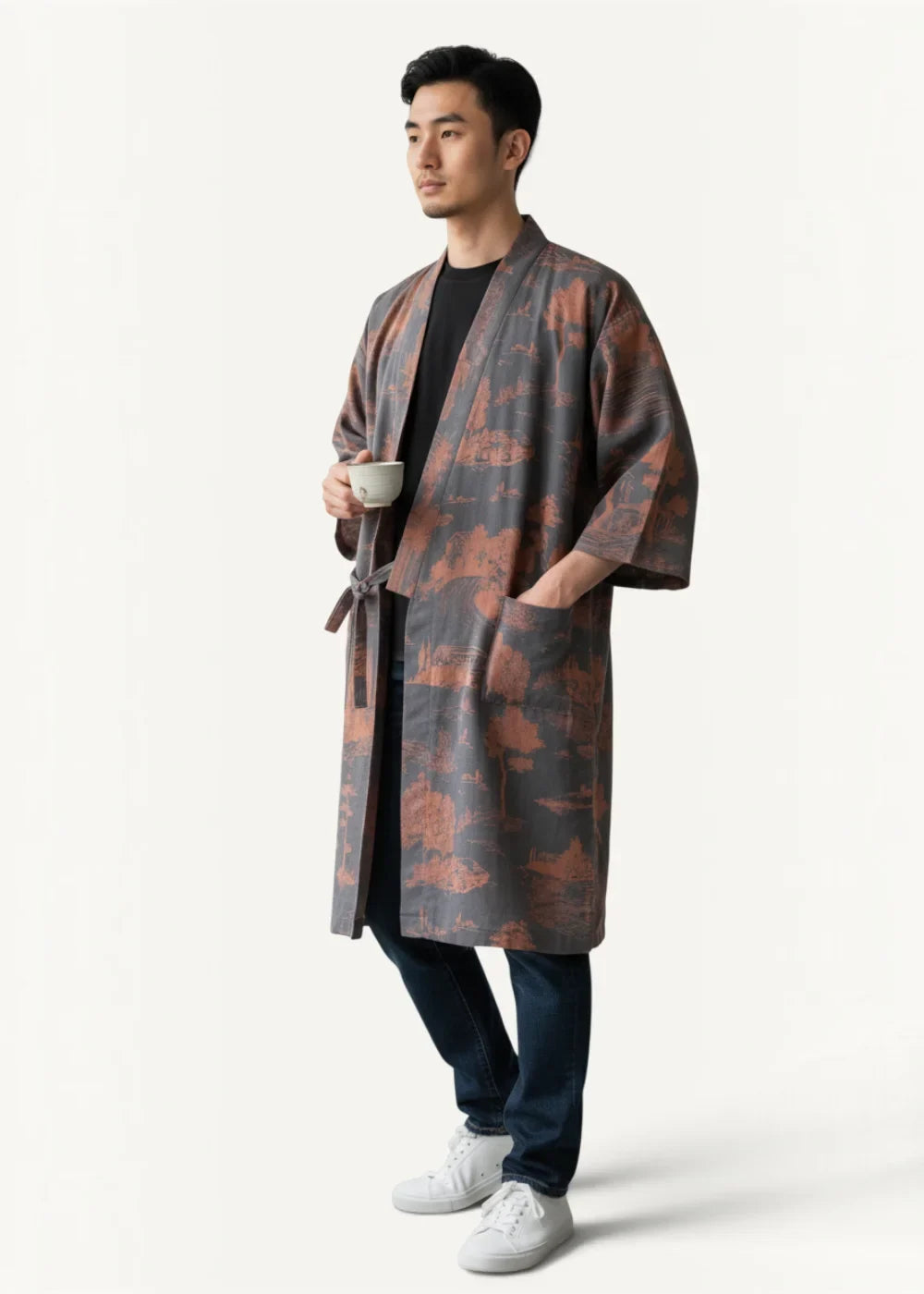 A man wearing a long dark gray and rust patterned silk kimono-style robe with wide sleeves and a tied belt