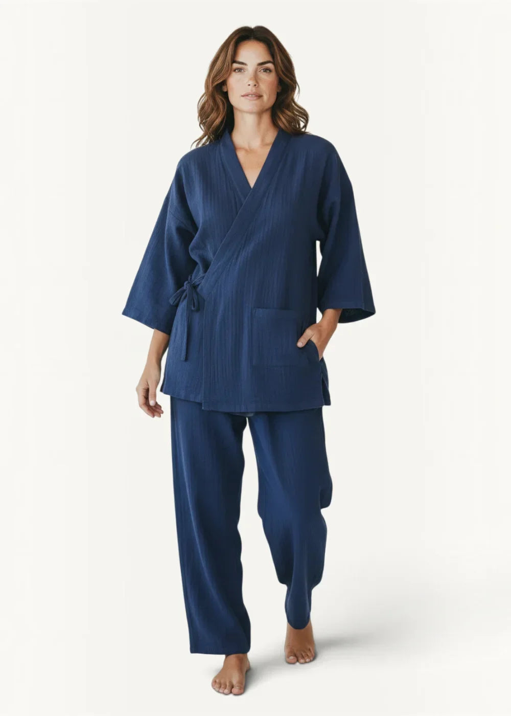 Woman wearing navy kimono pajamas, a kimono top with three quarter sleeves and matching wide leg pants