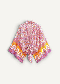 A flowing open-front pink kimono beach cover up with vibrant orange floral pattern and purple trim