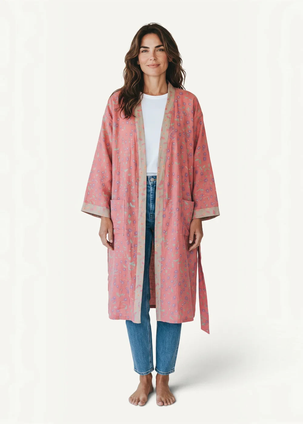 A soft pink kimono robe with long sleeves subtle floral pattern and beige trim along the edges