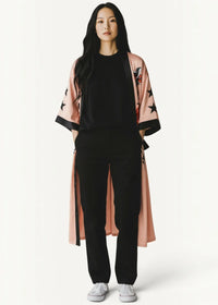 Pink satin kimono robe in soft silk with black star and bird embroidery worn over a black outfit
