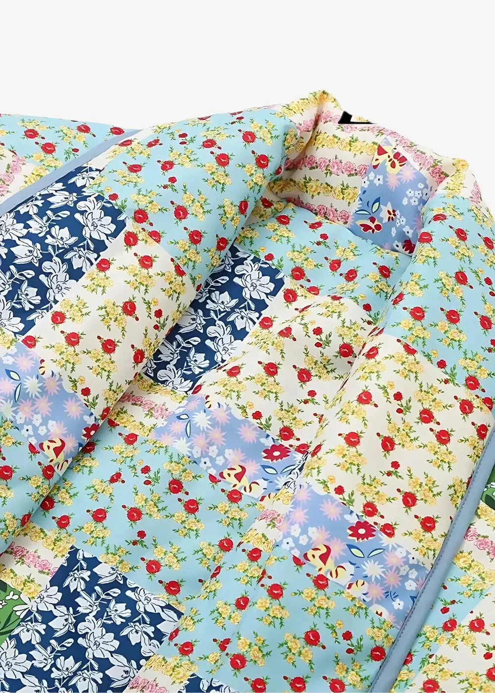 A soft patchwork baby nest with a floral pattern in light blue red yellow and navy displayed with a quilted kimono jacket women’s