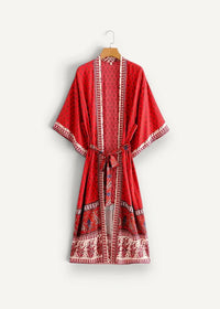 A vibrant red long sleeved kimono style robe with intricate white patterned trim and matching belt for beachwear