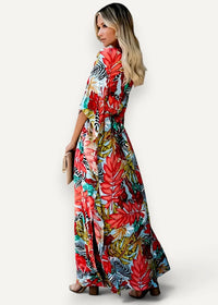 A red kimono dress featuring a vibrant tropical print maxi style with bold red green and black leaves on light blue fabric