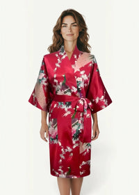 A vibrant red satin robe for women featuring a floral and peacock pattern tied at the waist with a matching belt
