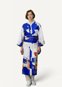 A woman wearing a vibrant blue and white satin dressing robe with traditional Japanese geisha and nature illustrations