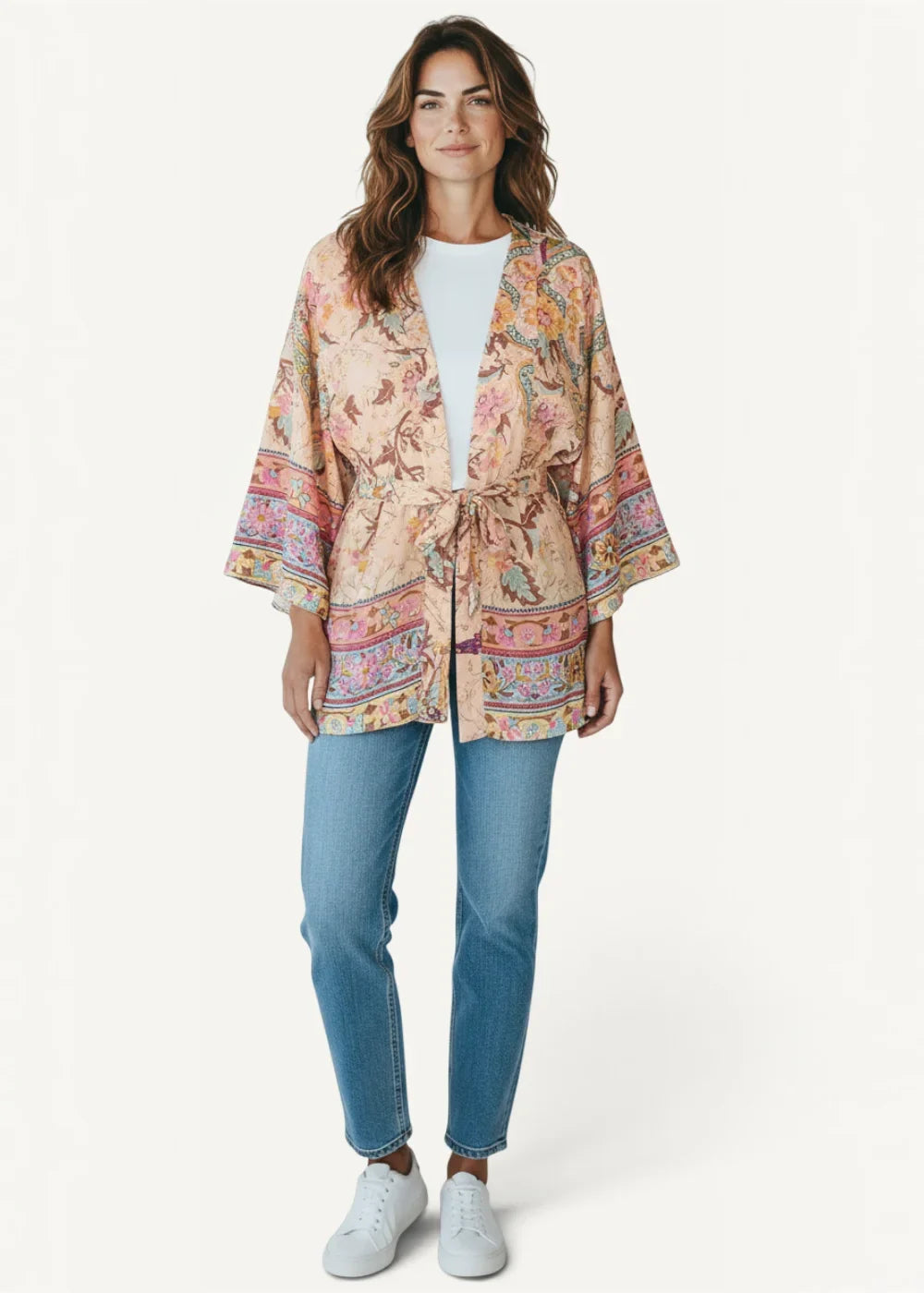 A soft beige short kimono dress with flowing fabric wide sleeves and vibrant floral paisley patterns in pink orange and green