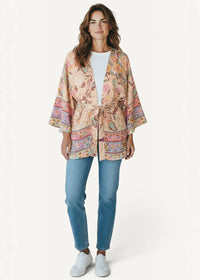 A soft beige short kimono dress with flowing fabric wide sleeves and vibrant floral paisley patterns in pink orange and green