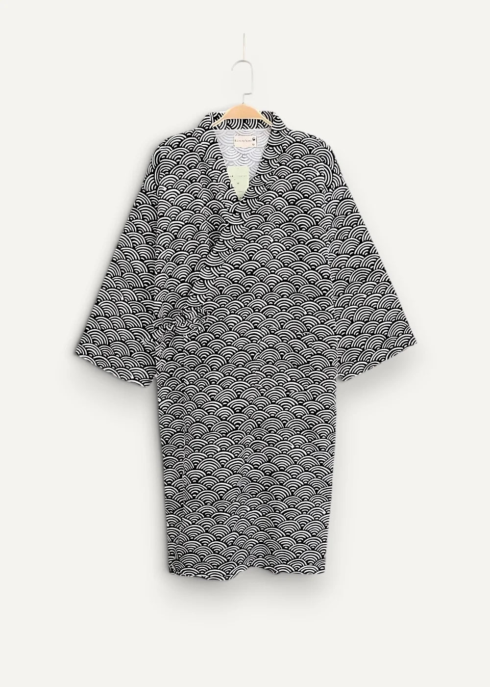 Black and white wave-patterned cotton short yukata kimono hanging on a wooden hanger showing the front side