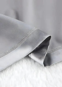 Silver silk satin robe showing smooth glossy fabric with precise stitching along the edge